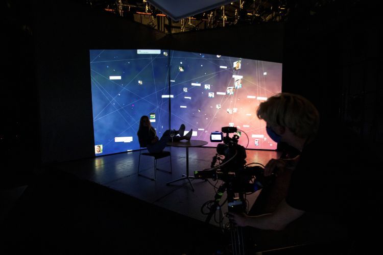 Silhouetted actor and camera operator in front of a video projected background
